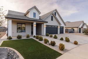 View of front of house with covered porch, brick siding, a front yard, concrete driveway, and an attached garage