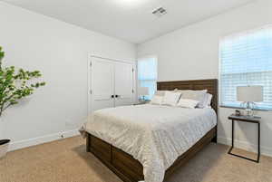Bedroom with light carpet and a closet