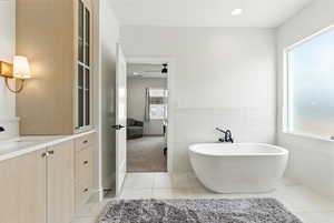 Full bath featuring plenty of natural light, a freestanding tub, tile patterned floors, vanity, and tile walls