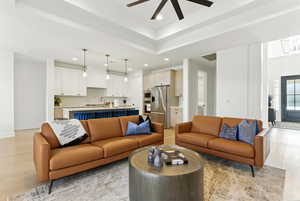Living area featuring recessed lighting, light wood finished floors, ceiling fan, and a raised ceiling