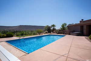 View of pool with a hot tub, a patio, and a mountain view