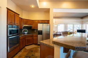 Kitchen with tile countertops, a breakfast bar, stainless steel appliances, recessed lighting, and tasteful backsplash