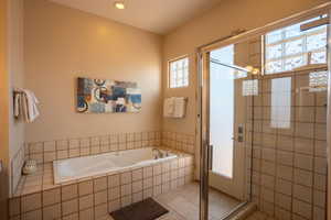 Bathroom featuring a bath, a stall shower, tile patterned flooring, and recessed lighting