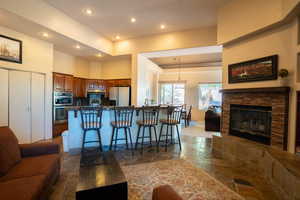 Kitchen with open floor plan, stone tile flooring, a kitchen breakfast bar, recessed lighting, and appliances with stainless steel finishes