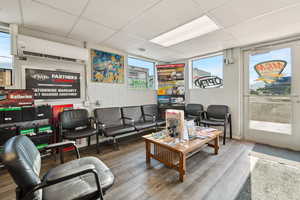 Living area with wood finished floors, a paneled ceiling, and a wall mounted air conditioner