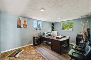 Office with a textured ceiling and dark wood finished floors
