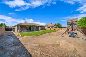 Fenced backyard featuring a patio and a playground