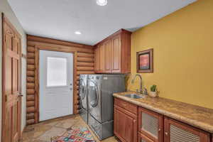 Washroom with separate washer and dryer, cabinet space, log walls, a textured ceiling, and recessed lighting