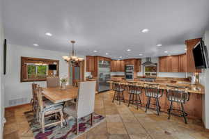 Dining room with stone tile flooring, recessed lighting, and a chandelier