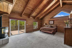 Primary bedroom with a wood stove, access to exterior, a wooden ceiling with exposed beams, rustic walls, and carpet floors