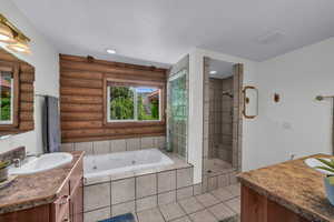 Full primary bath with healthy amount of natural light, vanity, a stall shower, a tub with jets, and log walls