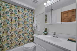 Full basement bathroom featuring a textured ceiling, vanity, and shower / bath combo with shower curtain