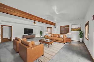 Living area featuring beamed ceiling, finished concrete flooring, and ceiling fan