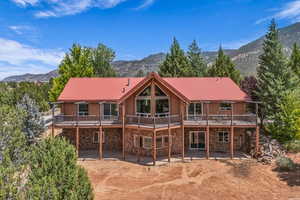 Rear view of property featuring stone siding, a patio area, a metal roof, and a deck with mountain view