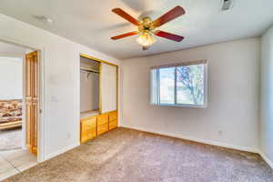 Unfurnished bedroom with light colored carpet, a closet, and ceiling fan