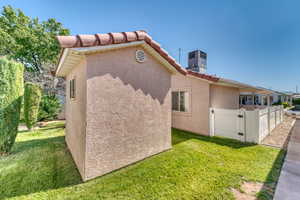View of side of property featuring stucco siding, a tiled roof, and a gate