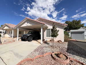 View of front of property with a carport, stucco siding, concrete driveway, and a tiled roof