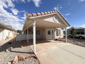 View of front of house featuring stucco siding, a carport, a tile roof, a gate, and driveway