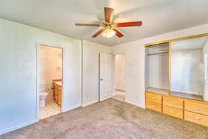 Unfurnished bedroom with a closet, light colored carpet, connected bathroom, and ceiling fan