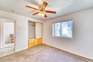 Unfurnished bedroom featuring light carpet, a closet, and ceiling fan
