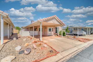 View of front of property featuring an attached carport, driveway, stucco siding, and a chimney