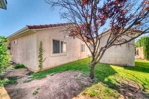 View of side of property with stucco siding, a lawn, and a tile roof
