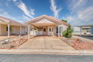 Mediterranean / spanish house featuring a tiled roof, concrete driveway, stucco siding, a gate, and an attached carport