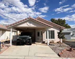 View of front facade featuring a carport, concrete driveway, a tiled roof, and stucco siding