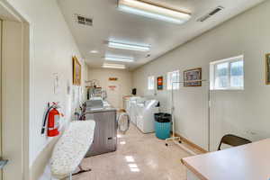 Community laundry with separate washer and dryer, light flooring, and a textured ceiling