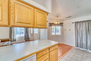 Kitchen featuring a chandelier, light brown cabinetry, light tile patterned floors, hanging light fixtures, and a textured ceiling
