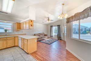 Kitchen with light brown cabinets, light countertops, a chandelier, open floor plan, and lofted ceiling