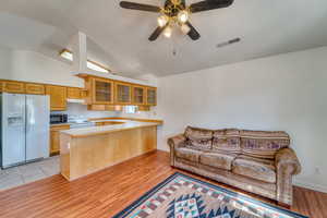 Kitchen featuring white appliances, a peninsula, vaulted ceiling, glass insert cabinets, and light countertops