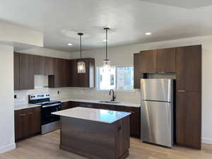 Kitchen featuring stainless steel appliances, light wood-type flooring, light countertops, a kitchen island, and recessed lighting