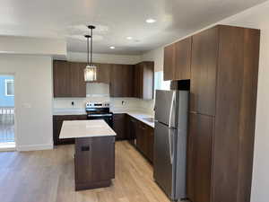 Kitchen featuring stainless steel appliances, light wood-type flooring, light countertops, a kitchen island, and recessed lighting