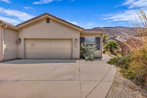 View of front of property with concrete driveway, a garage, and stucco siding