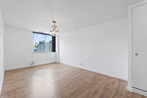 Empty room featuring a chandelier and wood finished floors