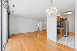Kitchen with brown cabinetry, freestanding refrigerator, light wood-style flooring, and black oven