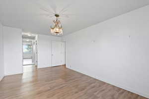 Empty room featuring a chandelier and light wood-type flooring