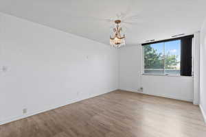 Unfurnished room with wood finished floors and a chandelier