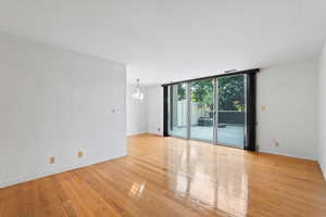 Spare room featuring a wall of windows, a chandelier, and light wood-style flooring