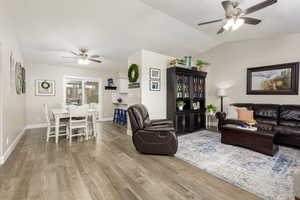 Living room with ceiling fan, wood finished floors, and vaulted ceiling
