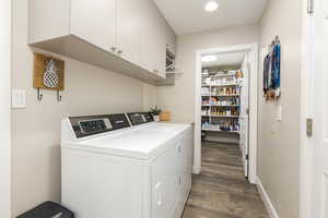 Laundry room with cabinet space, wood finished floors, and washing machine and clothes dryer