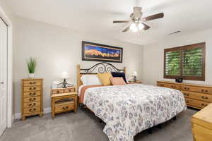 Bedroom with light colored carpet, a closet, and ceiling fan