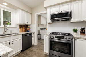 Kitchen featuring washer and clothes dryer, appliances with stainless steel finishes, decorative backsplash, and white cabinetry