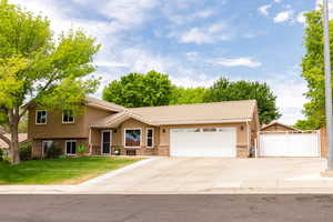 Split level home with a tile roof, concrete driveway, an attached garage, and stucco siding