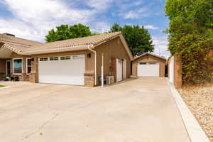 View of front of property with a tile roof, brick siding, stucco siding, an attached garage, and concrete driveway