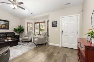 Living room featuring light wood finished floors, ceiling fan, and lofted ceiling