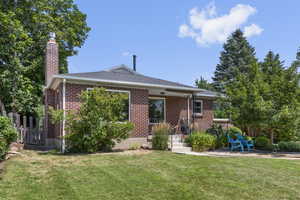 View of front of house with a chimney, brick siding, and roof with shingles
