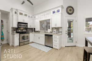 Kitchen featuring appliances with stainless steel finishes, a ceiling fan, tasteful backsplash, and light wood-style flooring