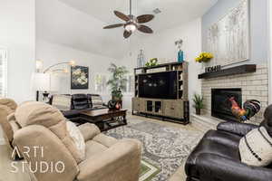 Living area featuring wood finished floors, ceiling fan, vaulted ceiling, and a brick fireplace